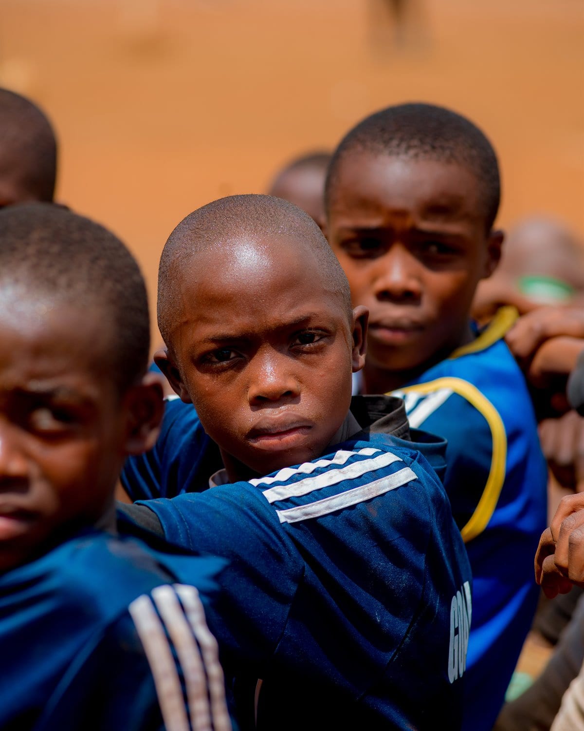 Goal Dream players resting together between drills, arms around one another's shoulders, one boy looking straight to camera